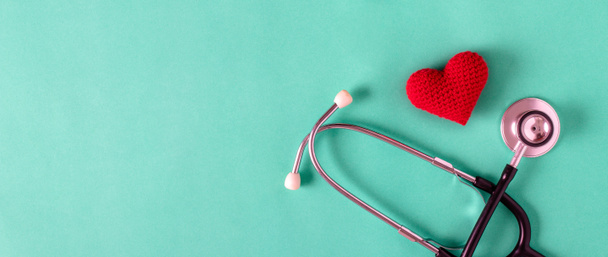 Heart made of red yarn with stethoscope on green background. health concept. - 写真・画像