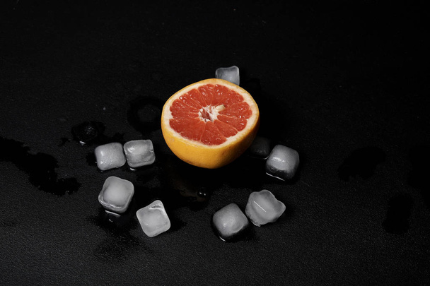 grapefruit slice and ice cubes on black background         - Zdjęcie, obraz