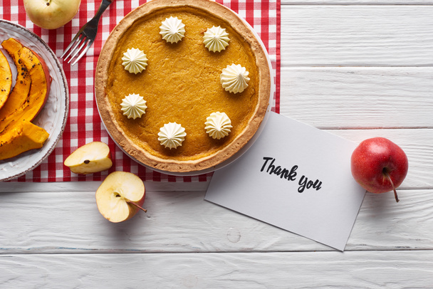 top view of pumpkin pie, ripe apples and thank you card on wooden white table - Photo, Image