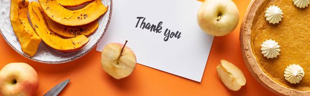 Draufsicht auf Kürbiskuchen, reife Äpfel und Dankeskarte auf orangefarbenem Hintergrund, Panoramaaufnahme - Foto, Bild