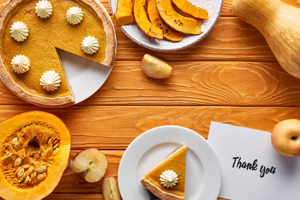 vue du dessus de tarte à la citrouille, pommes mûres et carte de remerciement sur table en bois
 - Photo, image