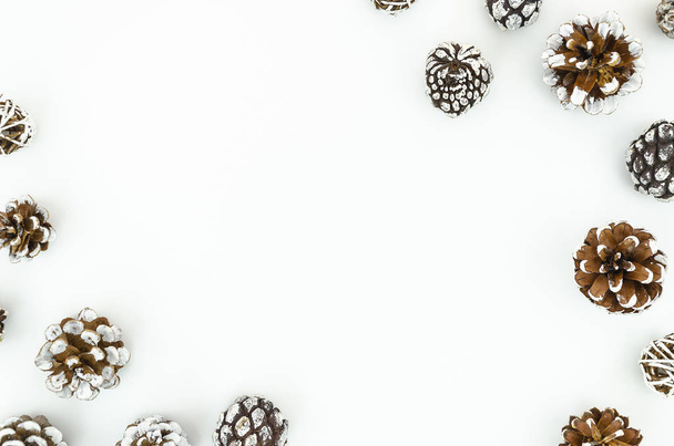 Xmas Frame mockup pine cones on white snowy background. Cones each in right top corner and left bottom corner. Top view with copy space - Foto, Bild