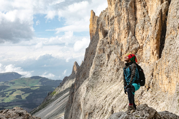 山の中の若い男がリュックを持って旅をする。イタリアのドロマイトの山の風景の美しい景色 - 写真・画像