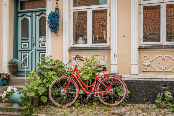 Ένα κόκκινο ρετρό ποδήλατο σε ένα πλακόστρωτο πεζοδρόμιο, που γέρνει τον τοίχο - Φωτογραφία, εικόνα