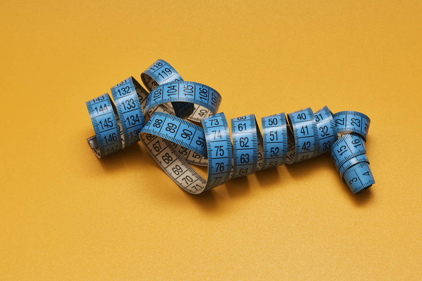 blue tape measure on yellow background - Фото, зображення