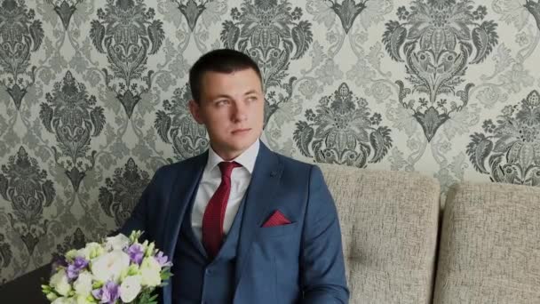 Young groom with a bouquet on the couch. - Footage, Video