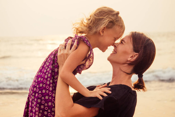 happy family at the beach. mother hugging child daughter and fly tourism with children.spf and sunscreen - Foto, imagen