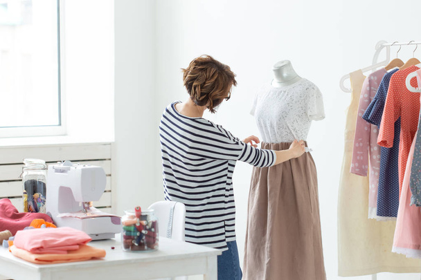Dressmaker, Small-Sized Enterprises, fashion designer and tailor concept - Working process, designer decorates the outfit on the mannequin - Fotó, kép