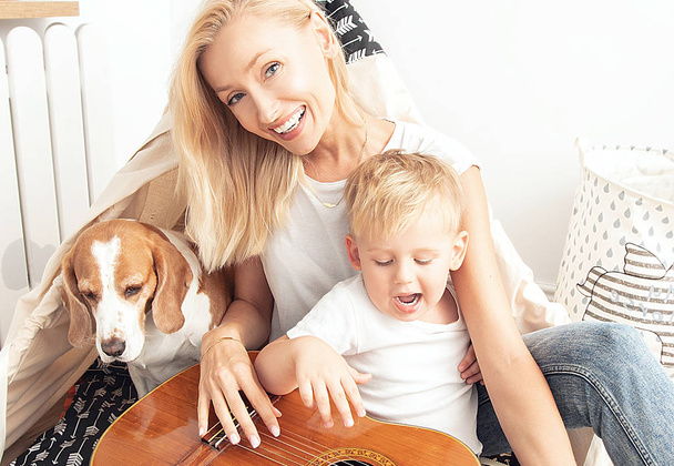 Little boy playing on guitar with mom . - Foto, afbeelding