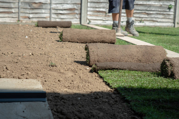 Rolls of new grass being laid out by landscaping gardeners in a home garden.  - Photo, Image