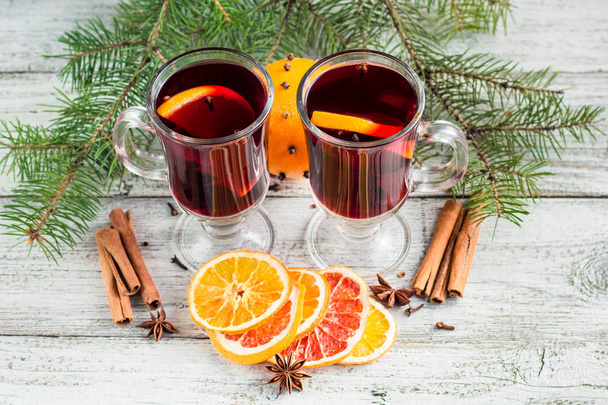 Χριστουγεννιάτικο καυτό κρασί με κανέλα πορτοκάλι και γλυκάνισο σε λευκό ξύλινο φόντο - Φωτογραφία, εικόνα