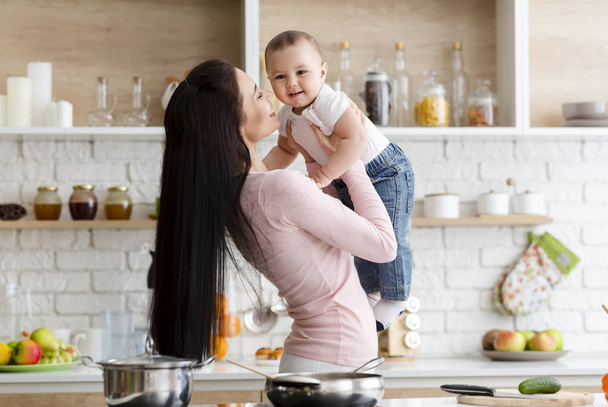 Madre jugando con adorable bebé hijo en la cocina
 - Foto, imagen