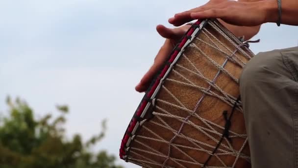 Een man speelt een Afrikaanse djembe drum tegen een blauwe lucht. Creativiteit, rust en ontspanning. Etnisch muziekinstrument tegen de lucht als concept van creatieve vlucht. - Video