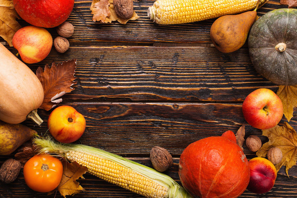 Különböző zöldségek, sütőtök, alma, körte, dió, paradicsom, kukorica, száraz sárga levelek a fából készült háttér. Őszi hangulat, másolás tér. Szüreti koncepció. - Fotó, kép
