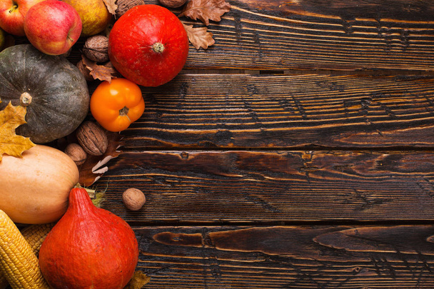 Different vegetables, pumpkins, apples, pears, nuts, tomatoes, corn, dry yellow leaves on wooden background. Autumn mood, copy space. Harvest concept. - Fotografie, Obrázek