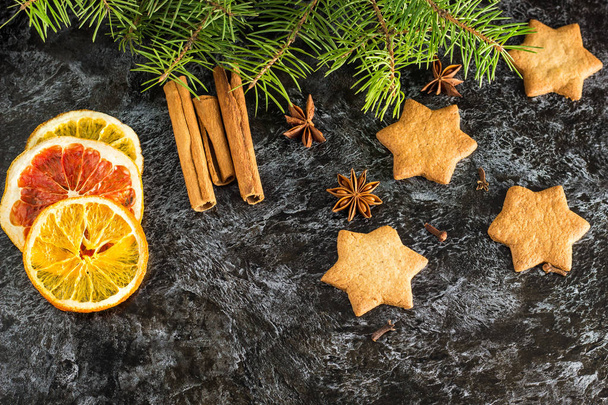 Kerst achtergrond met Fir Tree droge sinaasappel kaneel anijs en ster van peperkoek koekjes op donkere achtergrond. - Foto, afbeelding