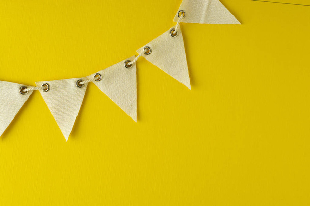 Flag triangular decorativ, party garland over colorful yellow background. Christmas party, birthday mockup with copy space. - Fotó, kép