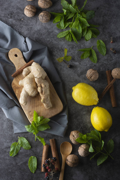 Ginger, lemons and mint leaves on dark background. Ginger tea, drink ingredients, cold and autumn time. - Fotó, kép