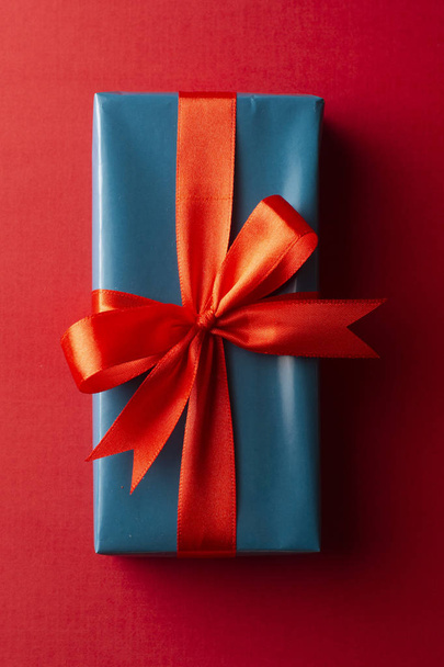 Blue gift box with red ribbon and bow isolated on red background, top view. Christms, party concept. - Foto, Bild