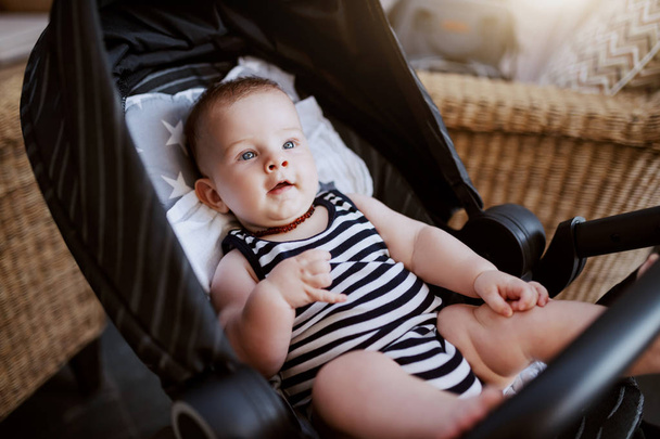Curieux adorable Caucasien 6 mois bébé garçon assis dans la poussette dans le café
. - Photo, image
