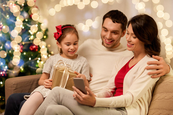 family with smartphone at home on christmas - Foto, Imagen