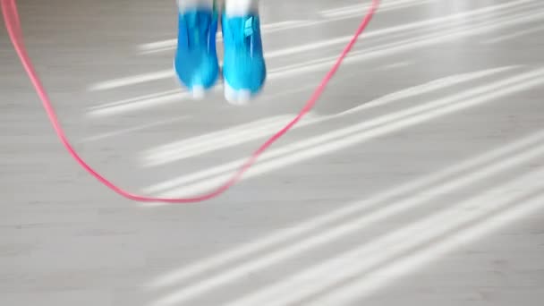 Nahaufnahme der Füße eines athletischen Mannes in blauen Turnschuhen, der sich dem Seilspringen nähert, nimmt und mit dem Springen beginnt - Filmmaterial, Video