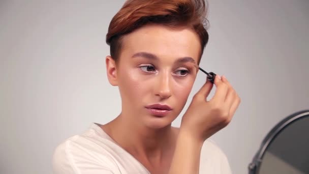 鏡の前で眉ブラシを使った髪型のきれいな若い女性 - 映像、動画