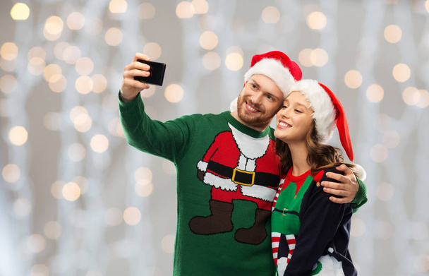 happy couple in christmas sweaters taking selfie - Foto, afbeelding