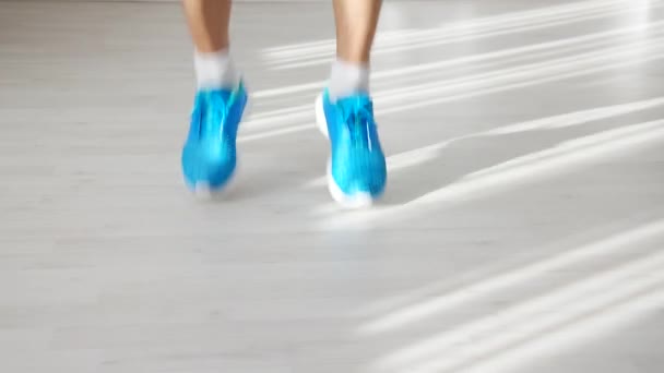 Nahaufnahme der Füße eines athletischen Mannes in blauen Turnschuhen, der sich dem Seilspringen nähert, nimmt und mit dem Springen beginnt - Filmmaterial, Video