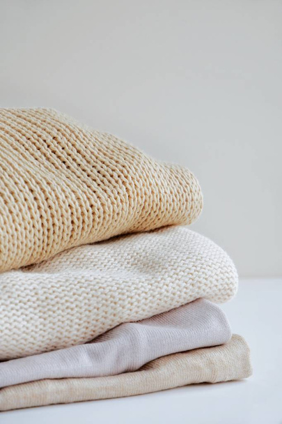 Warm sweaters in a pile, knitted texture, minimalism lifestyle, capsule wardrobe, autumn-winter season. With selective focus and copy space. - Photo, image