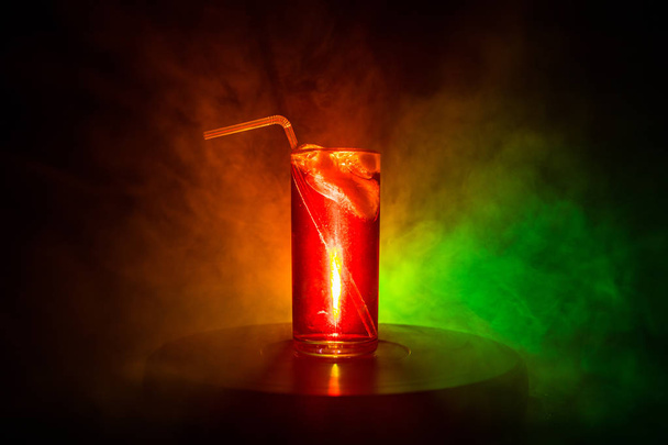 Sklenička z koktejlového skla na tmavém, zakouřené pozadí nebo barevný koktejl ve skle. Party v klubu. Smíšené světlo. - Fotografie, Obrázek