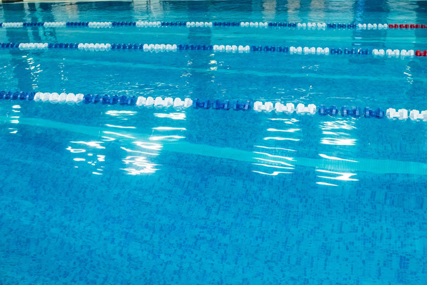 Empty lanes in a swimming pool.Indoor big blue swimming pool interior in modern minimalism style.Lanes of a competition. Healthy life, active sport - Photo, Image