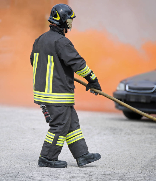 пожарный в форме, в шлеме и со сломанной машиной.
 - Фото, изображение