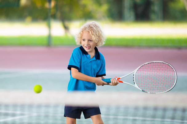 Child playing tennis on outdoor court - Foto, imagen