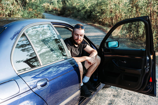 Cute, bearded man sitting in the front of the car, open door - Photo, Image