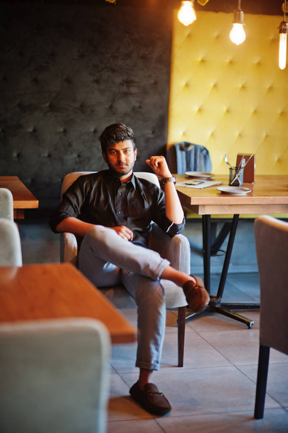 Confident young indian man in black shirt sitting at cafe. - Foto, Imagen