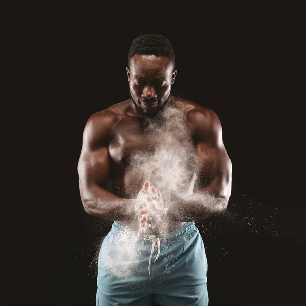 彼の手にタルカムパウダーを適用する若い黒人スポーツマン - 写真・画像