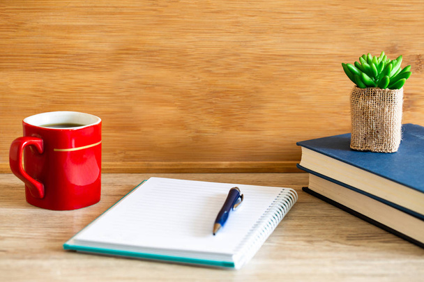 Notebook z zamkniętą księgą i filiżankę kawy na podłoże drewniane - Zdjęcie, obraz