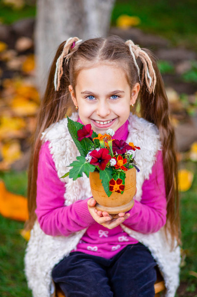 Cute happy girl with autumn bouquet of flowers in the garden on a sunny autumn day. - Foto, Imagem