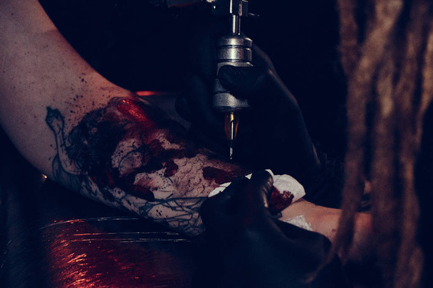 Sesión de fotos de primer plano de la fabricación de tatuajes en el estudio de fotografía oscura
 - Foto, Imagen