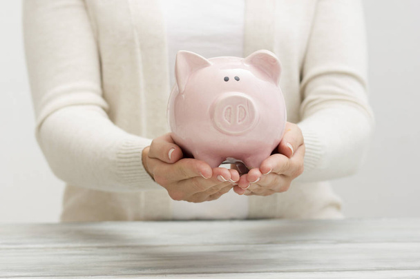 mão mulher colocando dinheiro moeda em porquinho para economizar dinheiro riqueza e conceito financeiro. - Foto, Imagem