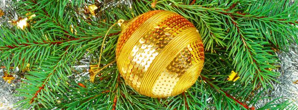 Christmas ornament. Bright golden ball on the background of a wr - Fotoğraf, Görsel