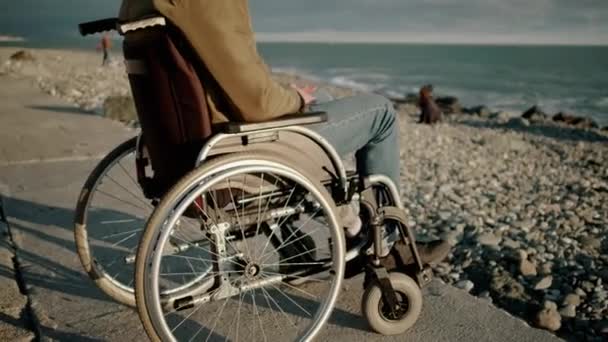 Handicapped man in wheelchair is alone with sea - Footage, Video