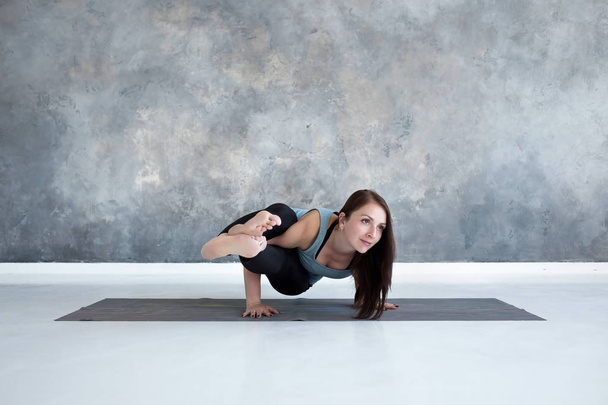 Giovane donna che tiene equilibrio braccio in Astavakrasana posa yoga
 - Foto, immagini