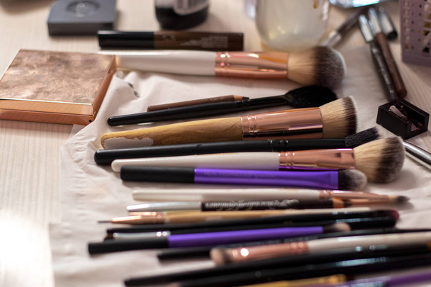 Erilaisia harjat ja meikki kyniä ja kosmeettinen kosmeettinen tasainen pöydällä pukuhuoneessa
 - Valokuva, kuva
