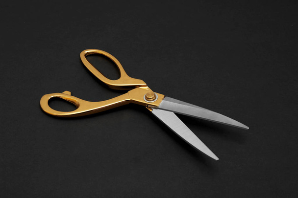 Stylish gold tailor scissors on black background - Foto, imagen