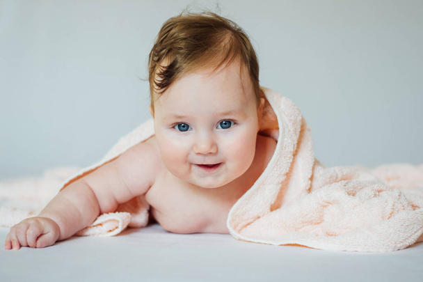 Schattige baby bedekt met een badhanddoek liggend op buik - Foto, afbeelding