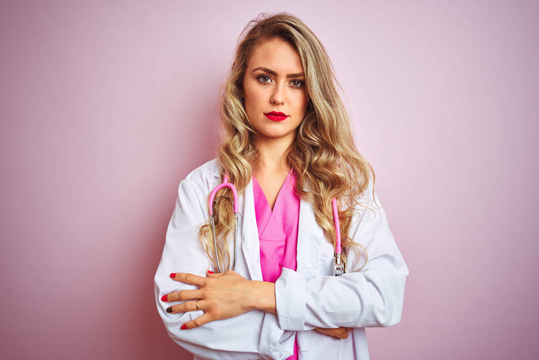 Young beautiful doctor woman using stethoscope over pink isolated background skeptic and nervous, disapproving expression on face with crossed arms. Negative person. - Photo, Image