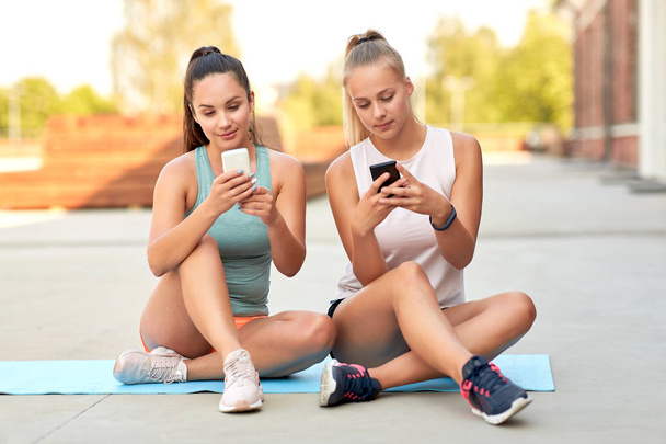 sporty women or friends with smartphone on rooftop - 写真・画像