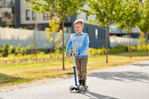 happy little boy riding scooter in city - Fotografie, Obrázek